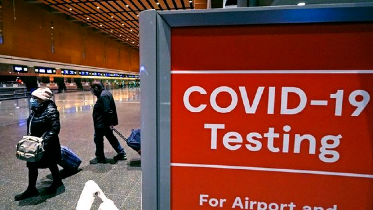 지난해 12월 보스턴 로건 공항 E 터미널의 코로나19 검사장 근처에서 여행객들이 표지판을 지나가고 있다. AP=연합뉴스