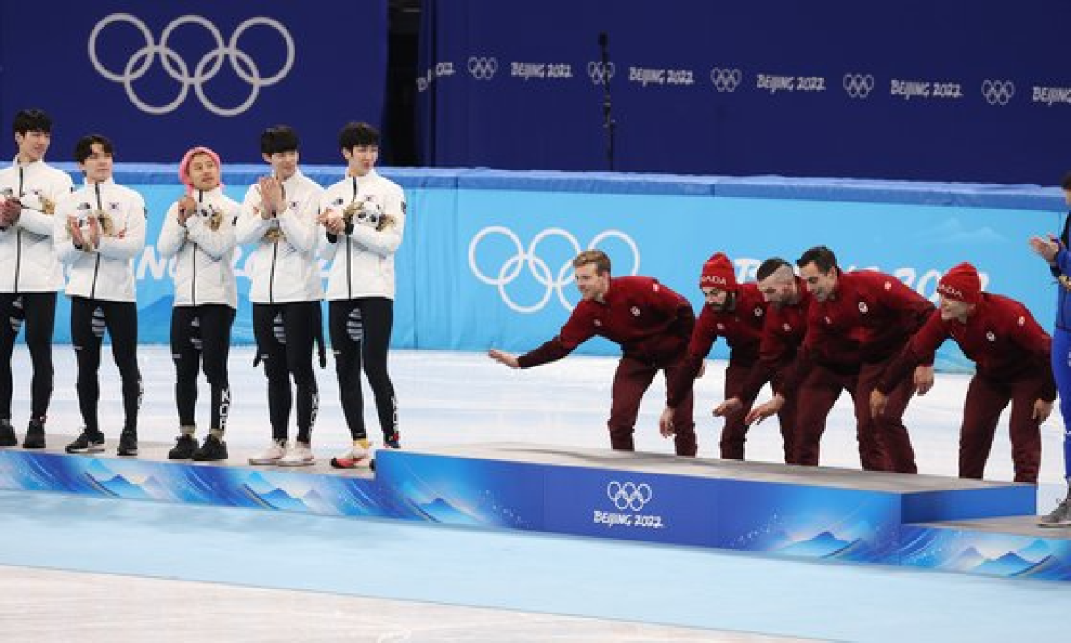 지난 16일 중국 베이징 캐피털 실내 경기장에서 열린 2022 베이징 겨울올림픽 쇼트트랙 남자 5000m 계주 결승에서 1위를 차지한 캐나다 대표팀 선수들이 경기 직후 열린 플라워 세리머니에서 금메달 단상에 오르다 바닥을 쓰는 동작을 하고 있다. 연합뉴스