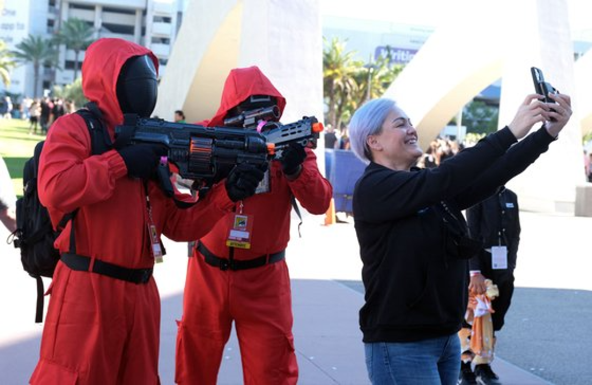지난달 26일 샌디에이고 코믹콘 특별판 행사에서 한 여성이 오징어게임 의상을 입은 참가자들과 기념 촬영을 하고 있따. [AFP=연합뉴스]