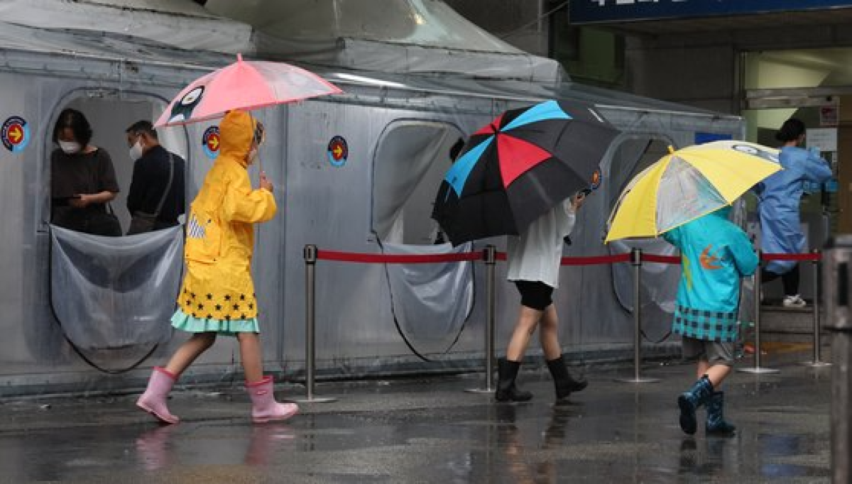 코로나 19가 확진자가 증가하고 있는 18일 시민들이 우산으로 장맛비를 피하며 부산 진구 부산진구보건소 선별진료소에서 길게 줄서서 검사 차례를 기다리고 있다. 송봉근 기자